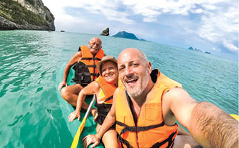 Senior mother and father with son taking selfie at kayak excursion in Thailand - Adventure travel in south east asia - Elderly and family concept of love sharing moments with parents - Warm vivid look