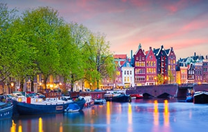 Boats in a                                                        canal in Amsterdam                                                        at sunset